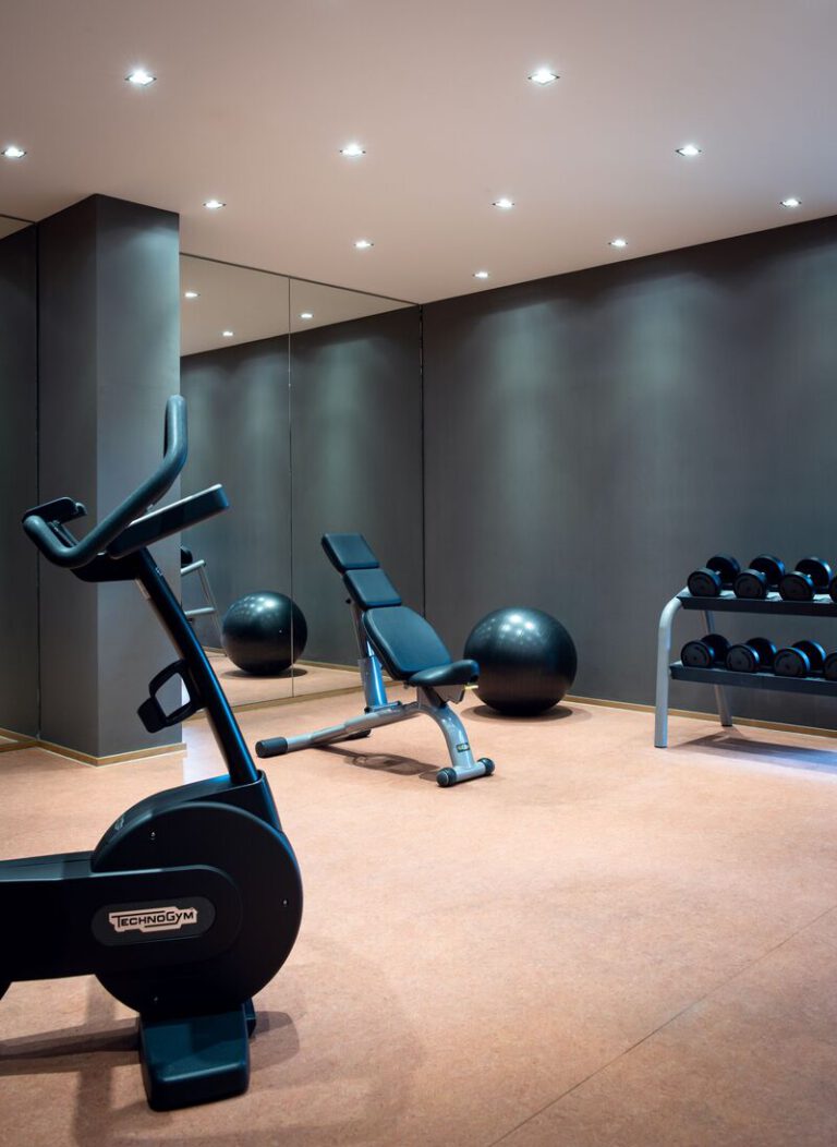 Hantelbank, Fitnessrad und Gymnastikball vor einem großen Spiegel – für sportlich Aktive im AMERON Köln Hotel Regent