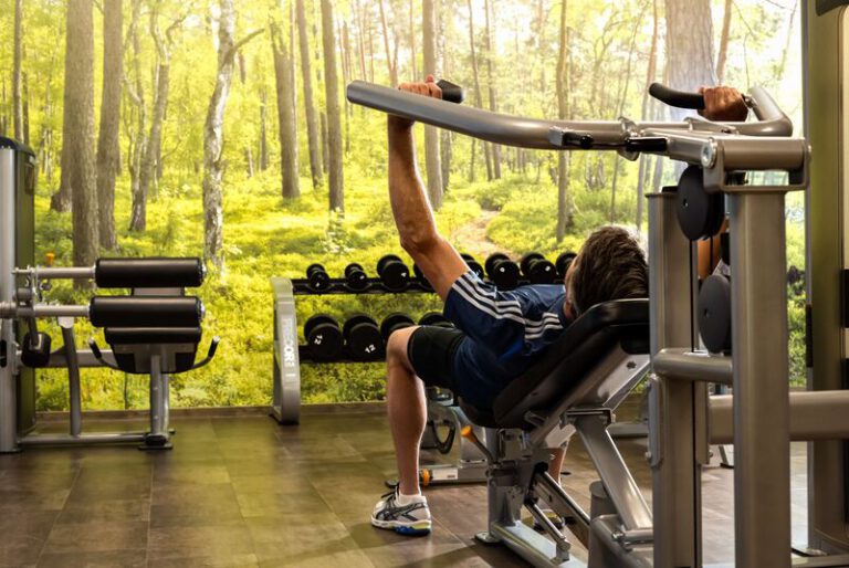Hotelgast trainiert an modernen Fitnessgeräten mit Blick auf eine beruhigende Waldlandschaft – aktive Erholung im Dorint An der Messe Köln