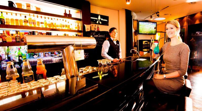 Barkeeper serviert einen farbenfrohen Cocktail an der edlen Hotelbar – einladende Atmosphäre für Drinks und Gespräche