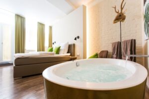 Doppelzimmer im 1st Floor Köln 2 mit Whirlpool, hellem Design und dekorativem Hirschkopf.